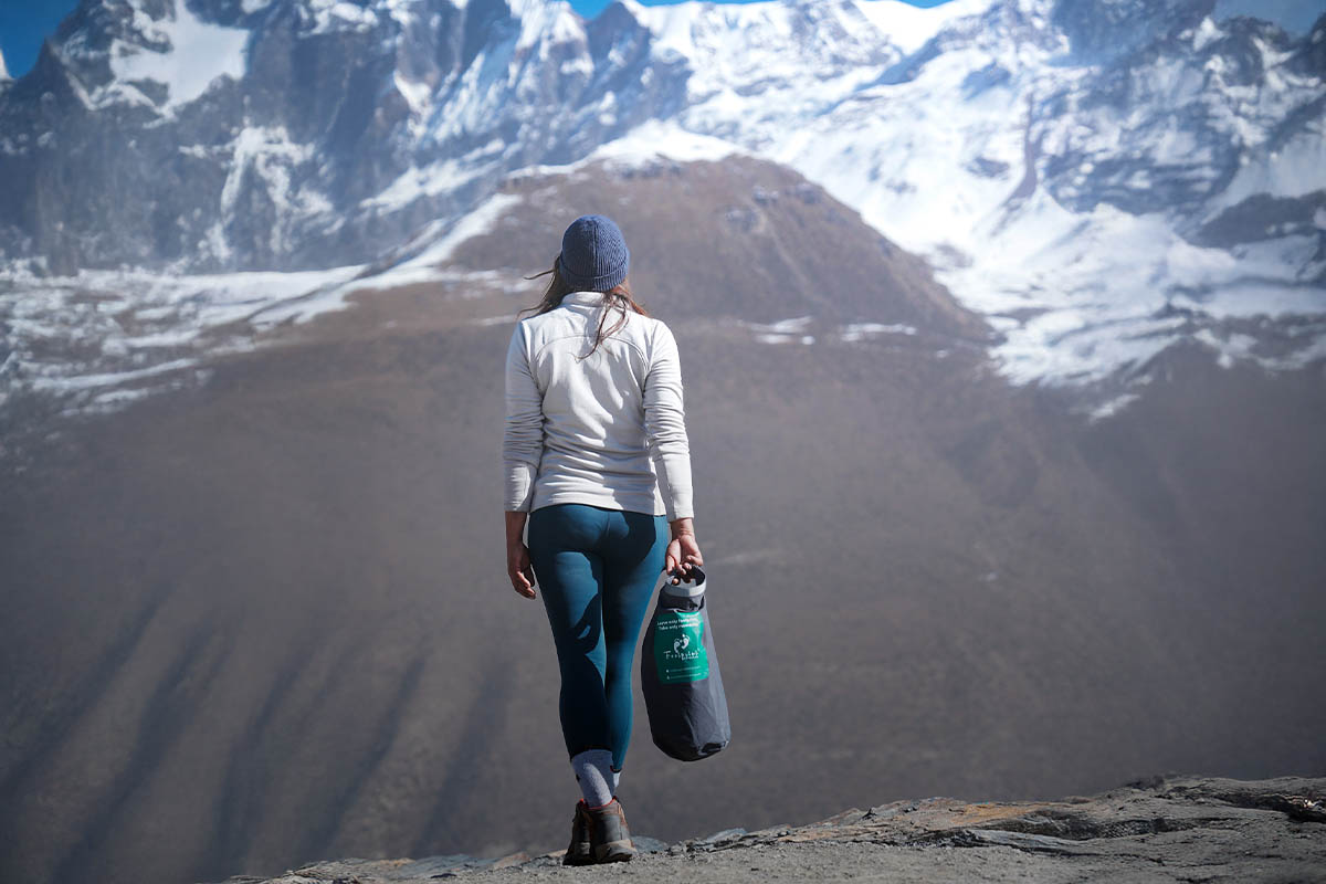 A hiker carrying a Footprint Adventure's Carryme bag, standing at a high-altitude glacier viewpoint in Annapurna.
